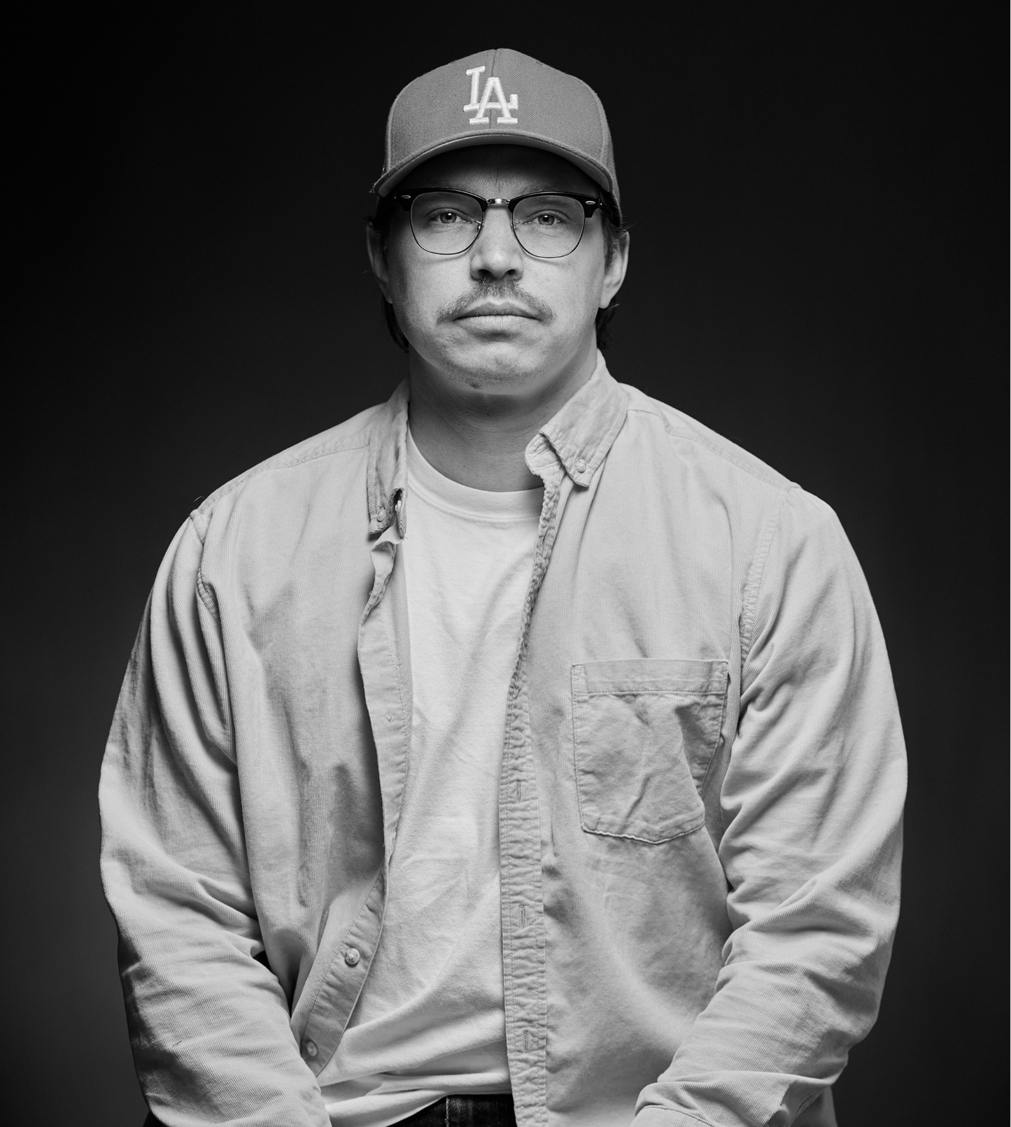 Person wearing a cap and glasses with a plain background